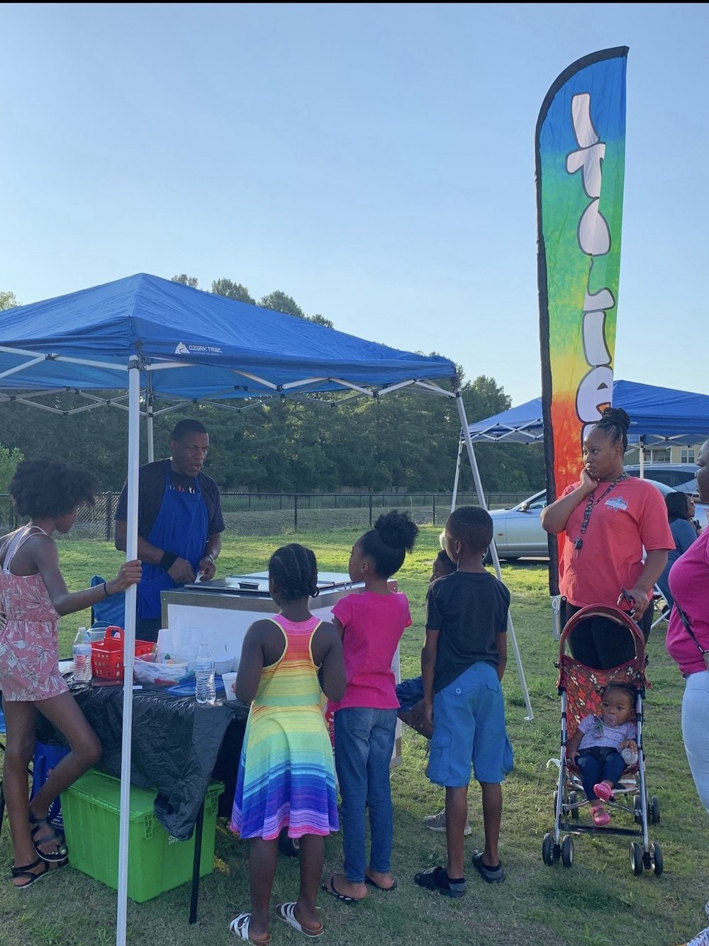 Kids lined up at the IcyScott cart with the branded flag